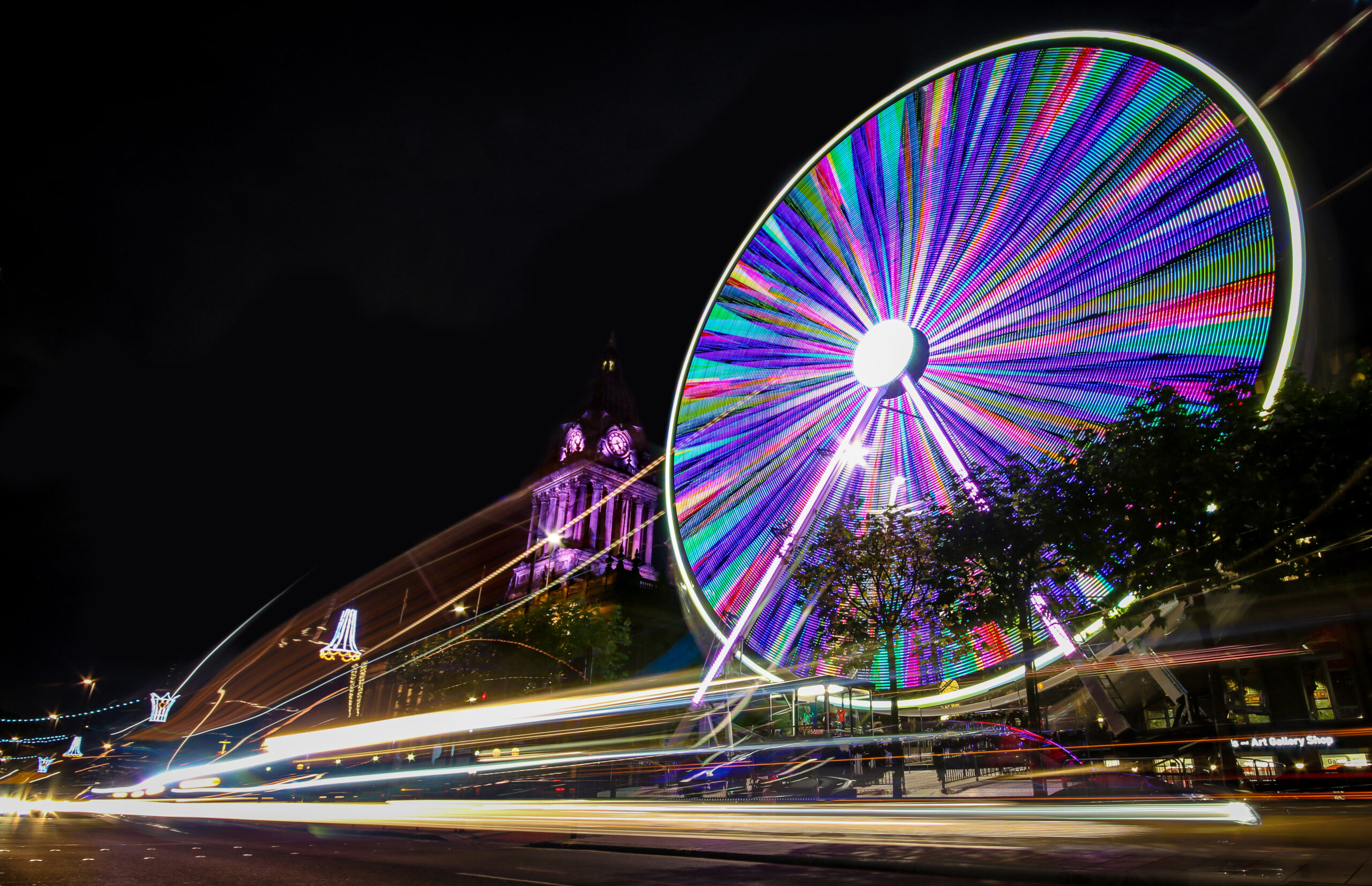 Night time image of the Leeds Wheel of Light lit up with the Town Hall in the background